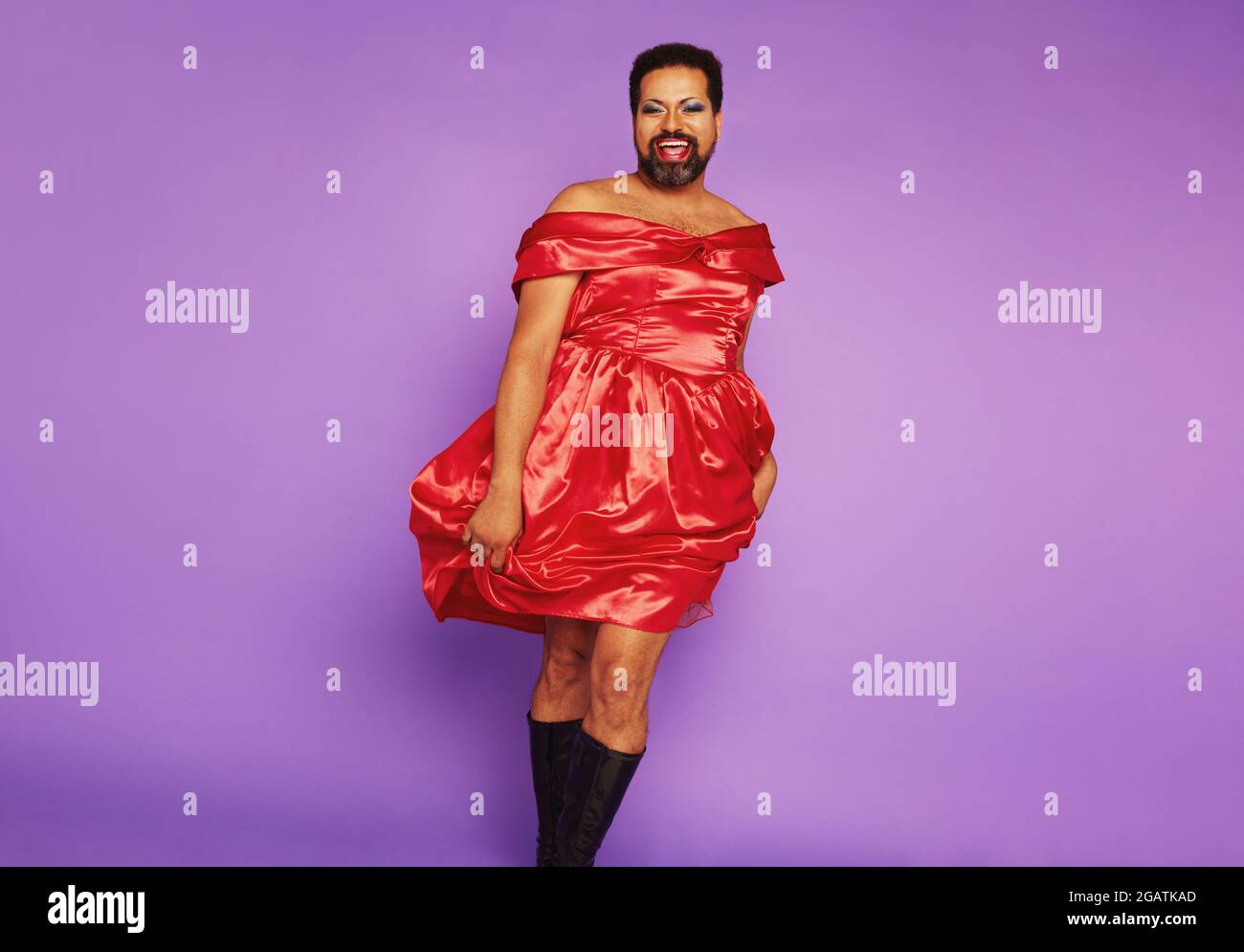 Modèle de queer debout dans une robe féminine. Homme de sexe fluide portant  une belle robe chantant sur fond violet Photo Stock - Alamy