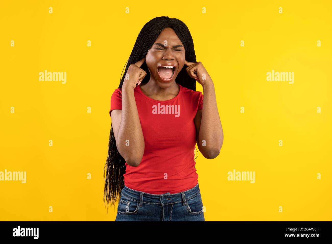 Emotive Black Femme criant couvrant les oreilles avec les doigts se tenant sur fond jaune. Photo de la dame hurlant en studio avec les yeux fermés. Je n'ai pas de Wa Banque D'Images