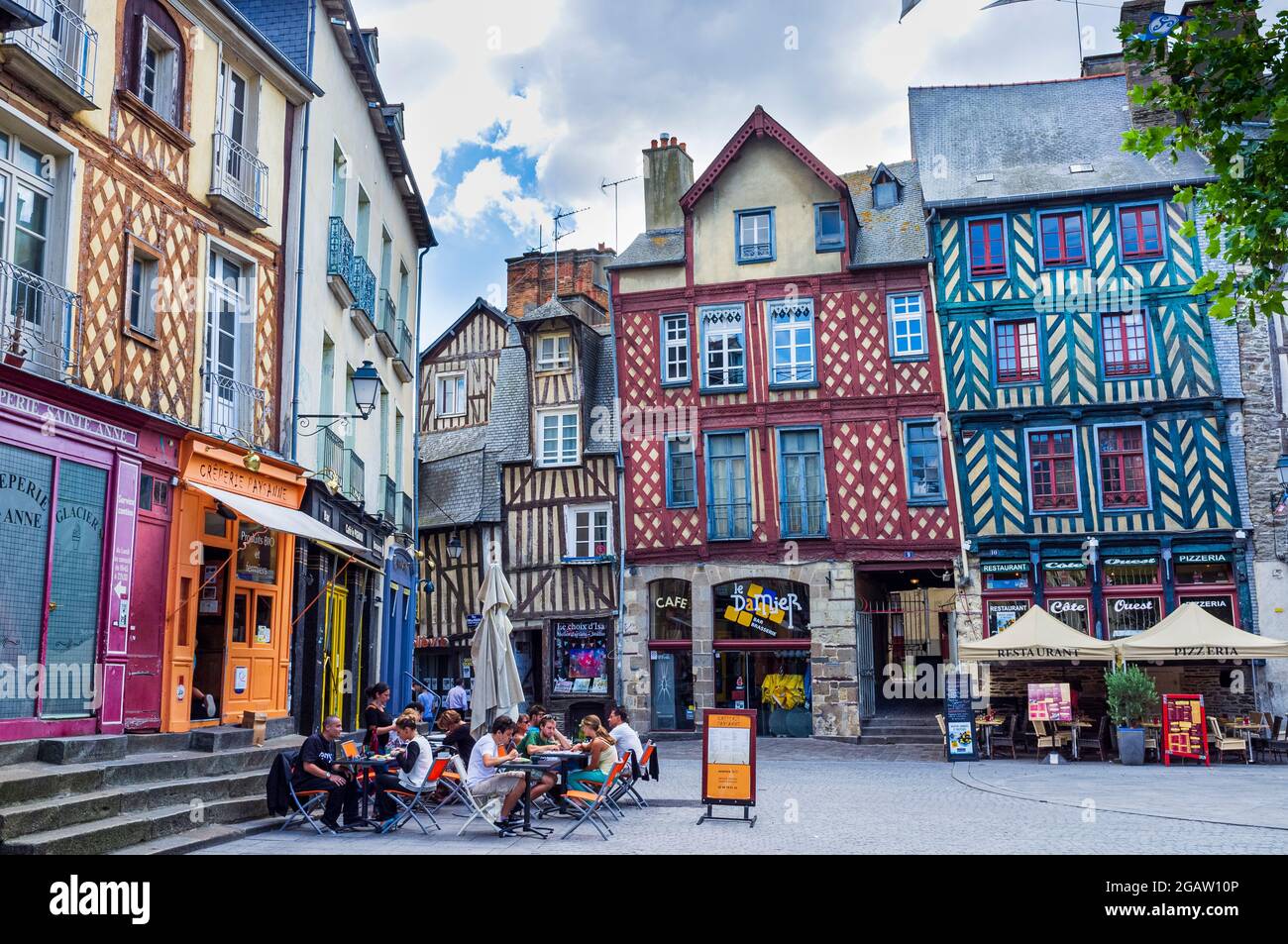 Bâtiments à colombages colorés avec des acheteurs à Rennes, Bretagne, France. Personnes assises dans des restaurants en plein air. Banque D'Images