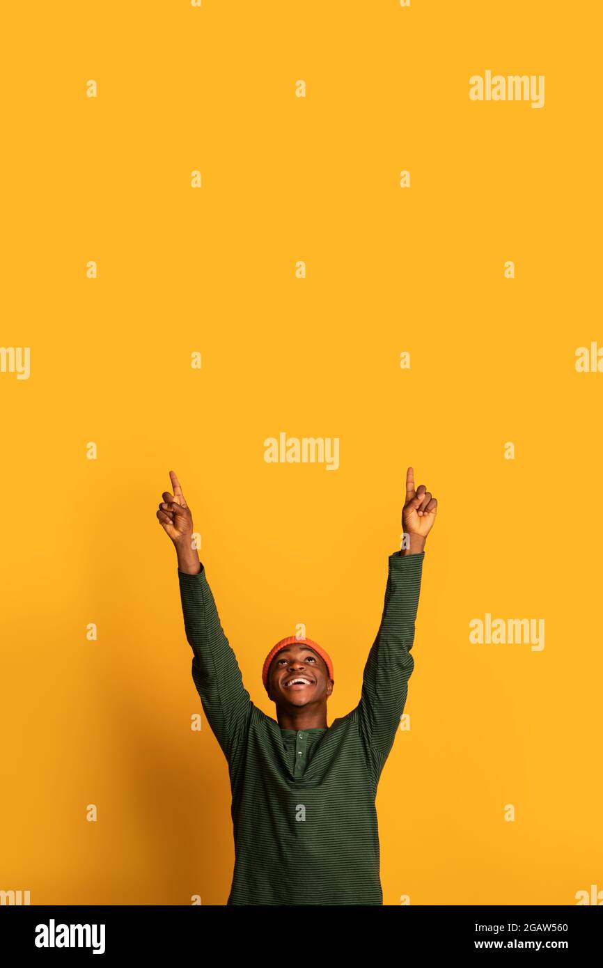 Vérifiez ceci. Joyeux homme afro-américain pointant vers le haut à l'espace de copie au-dessus de sa tête avec deux mains, heureux Noir Hipster homme démontrant la place libre pour Banque D'Images