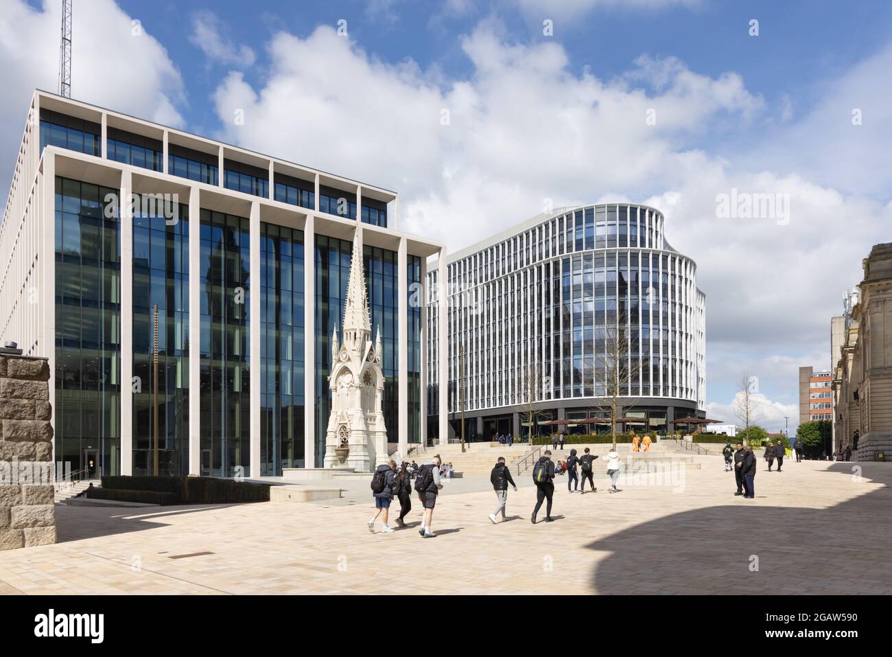 Birmingham, West Midlands, Royaume-Uni, 26 mai 2021 : un groupe de jeunes hommes passe devant le Mémorial de Chamberlain, dominé par des immeubles de bureaux modernes. Banque D'Images