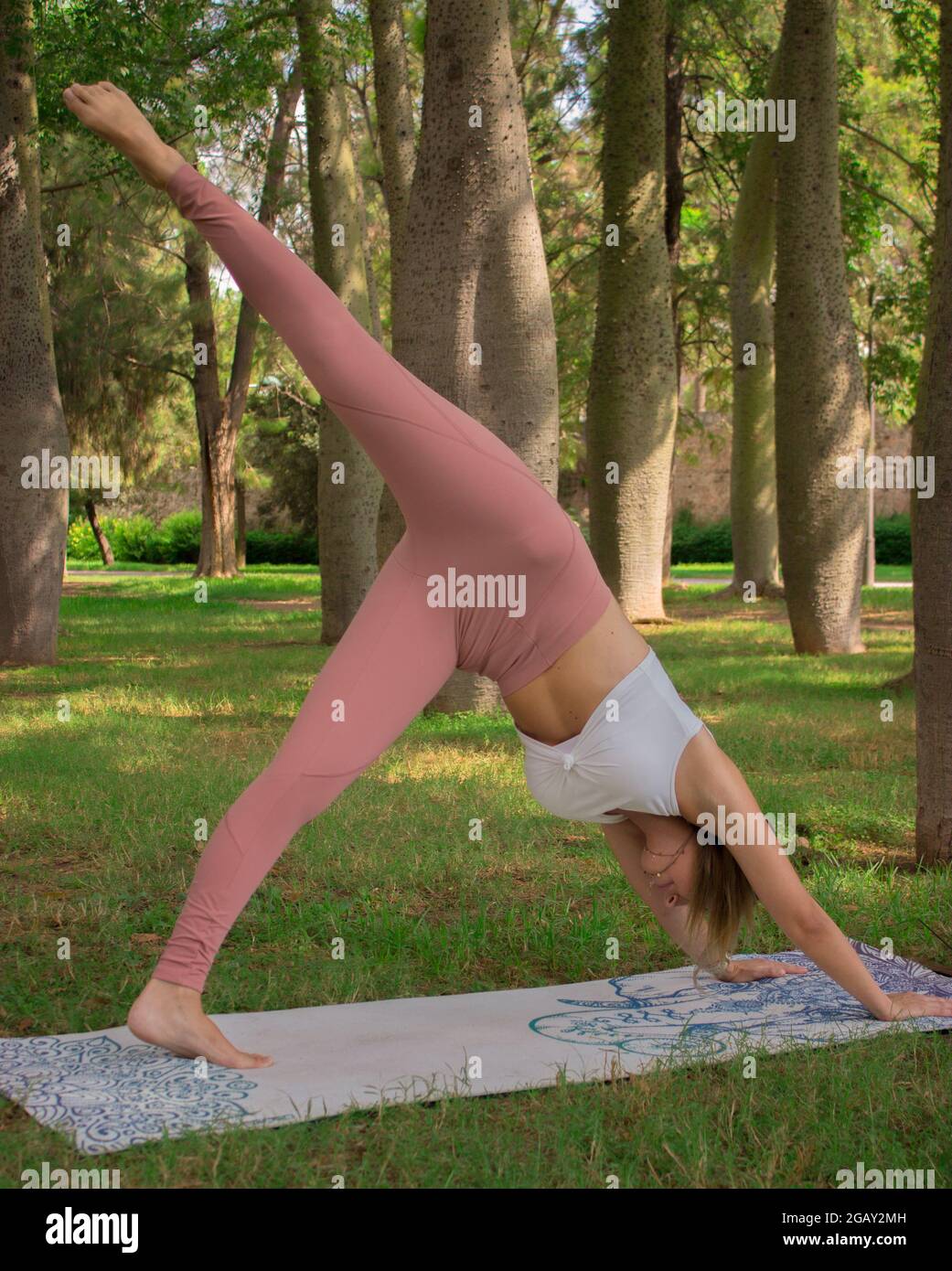 Image verticale jeune femme s'étirant après l'exercice de pilates à l'extérieur dans le parc de la ville dans une journée ensoleillée l'été. Pilates extérieur 2021. Banque D'Images