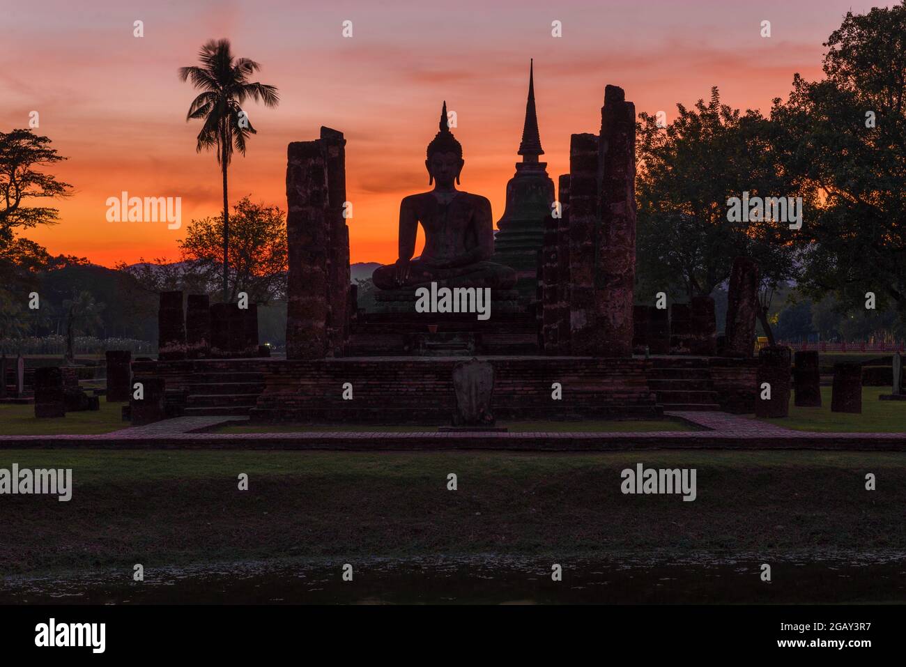 Sculpture du Bouddha sur les ruines du temple bouddhiste de Wat Chana Songkram en arrière-plan du coucher du soleil. Sukhothai, Thaïlande Banque D'Images