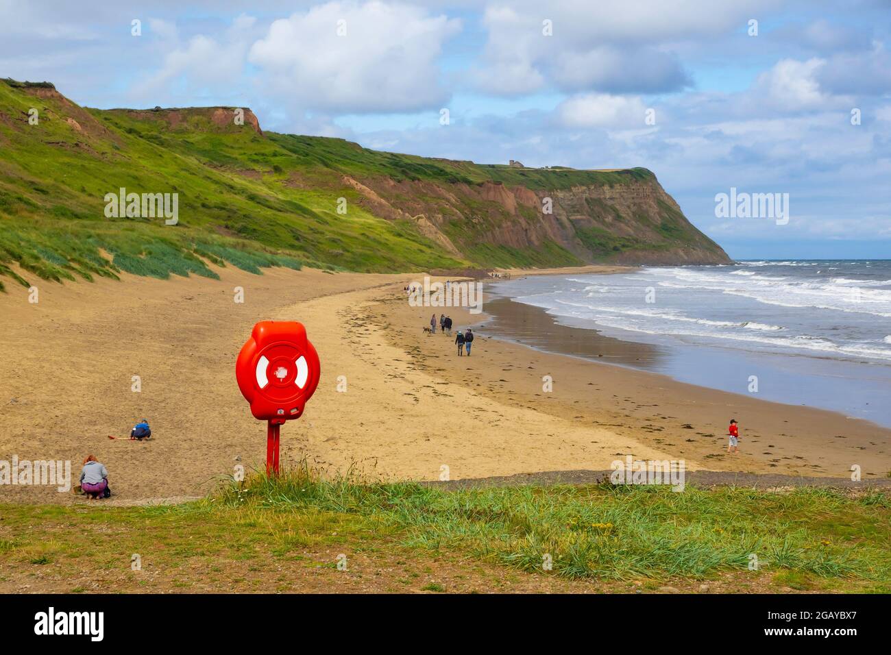 Les gens marchent le long de la plage préservée de Cattersty Sands à Skinningrove Cleveland Royaume-Uni et un homme marche son chien Banque D'Images