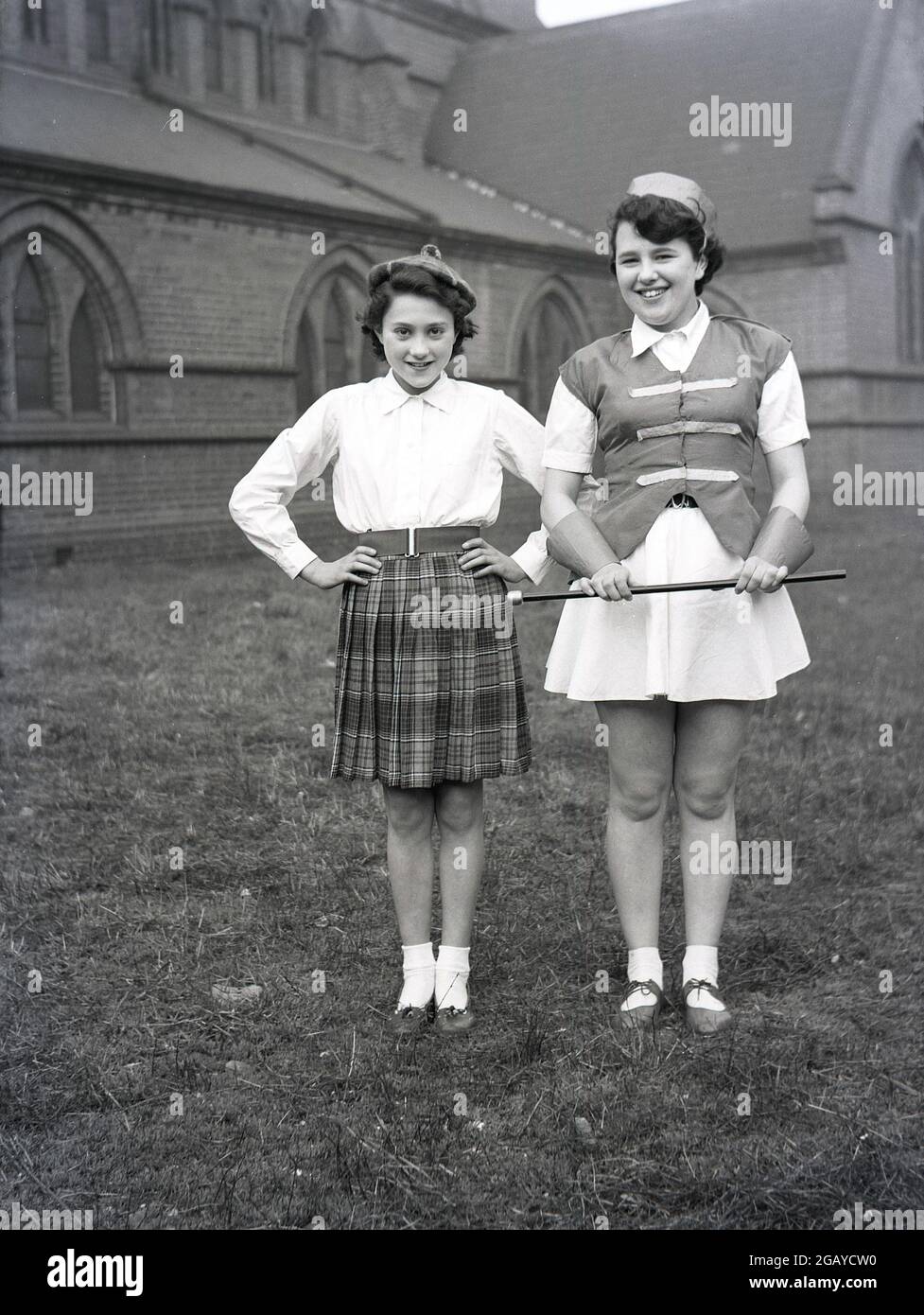 1956, historique, à l'extérieur dans le domaine d'une église, deux filles debout dans leurs costumes pour le Mai jour Carnval, Leeds, Angleterre, Royaume-Uni. Banque D'Images