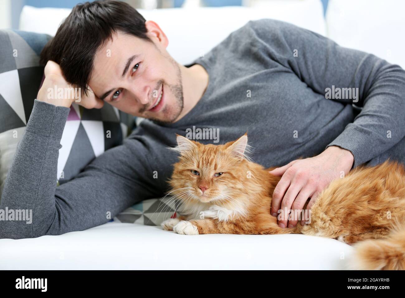 Jeune Homme Avec Chat Moelleux Allonge Sur Un Canape Photo Stock Alamy