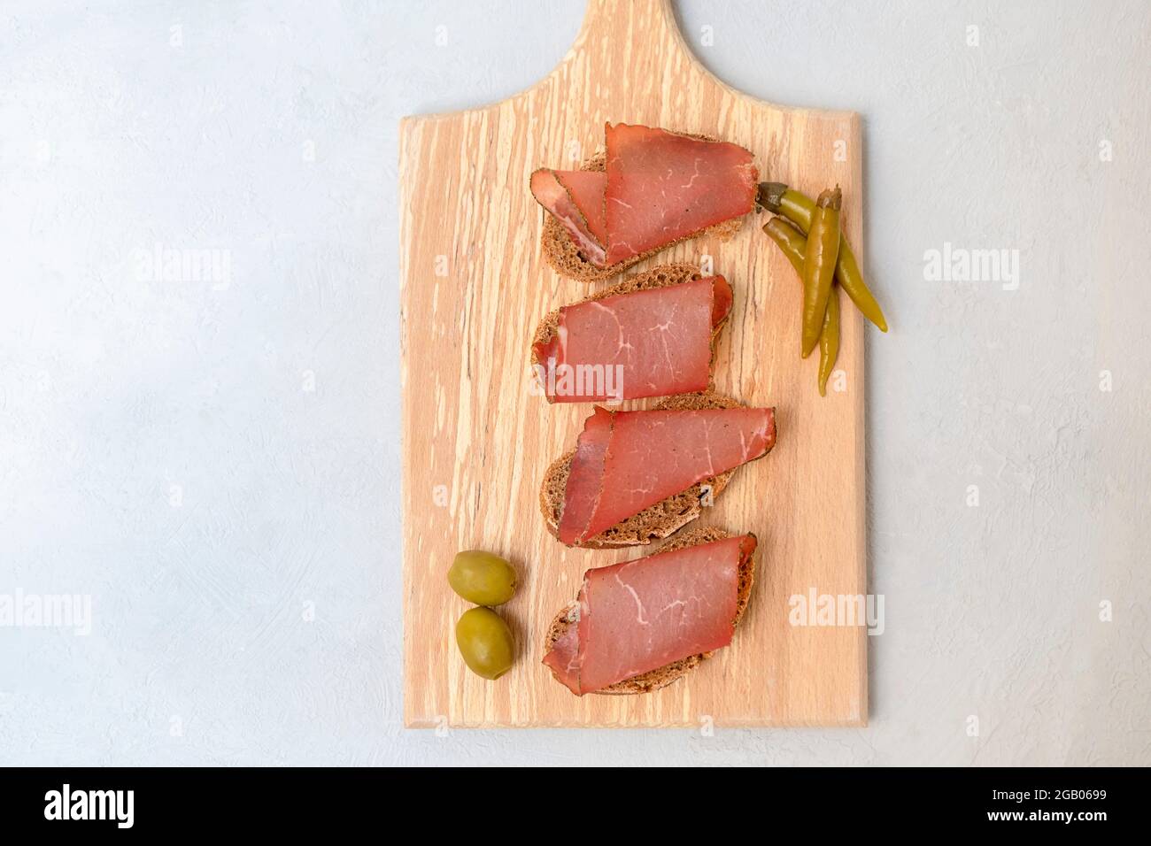 Vue de dessus des sandwiches avec des tranches de viande séchée servies sur le plan de coupe sur fond gris neutre Banque D'Images