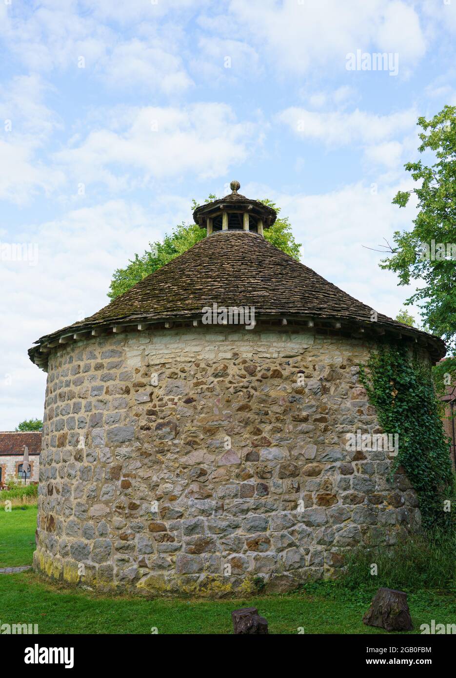 Un pigeonnier circulaire classé de grade II historique avec des murs en pierre caoutchoutée avec une coupole ouverte et un toit conique en pierre-ardoise Banque D'Images