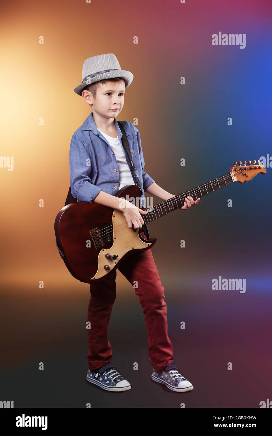 Petit garçon qui joue de la guitare sur un arrière-plan lumineux sombre  Photo Stock - Alamy