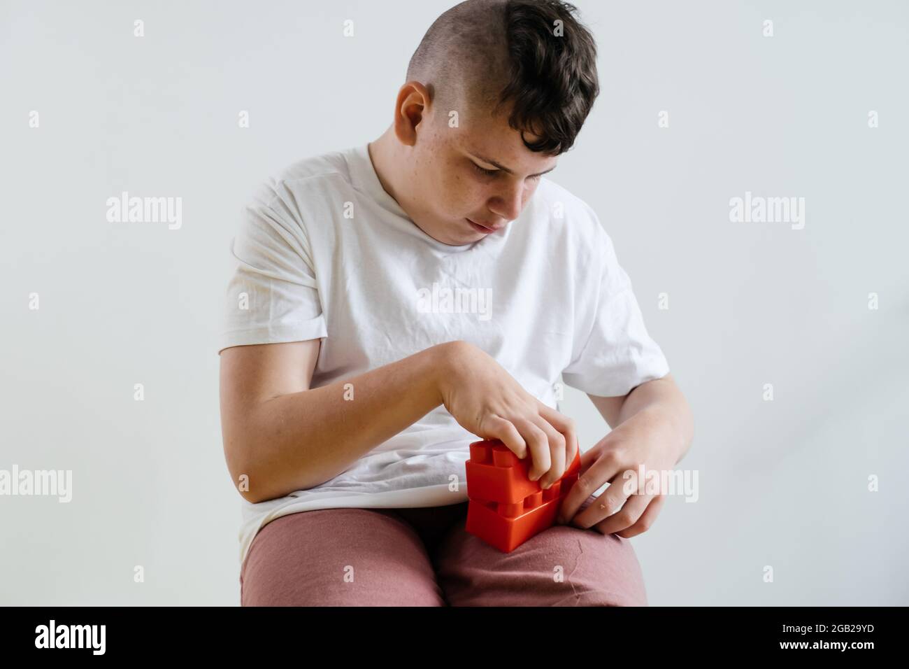 Enfant adolescent handicapé construire à partir de blocs garçon avec paralysie cérébrale faire des activités pour les enfants avec des besoins spéciaux sur fond blanc. Créativité Banque D'Images