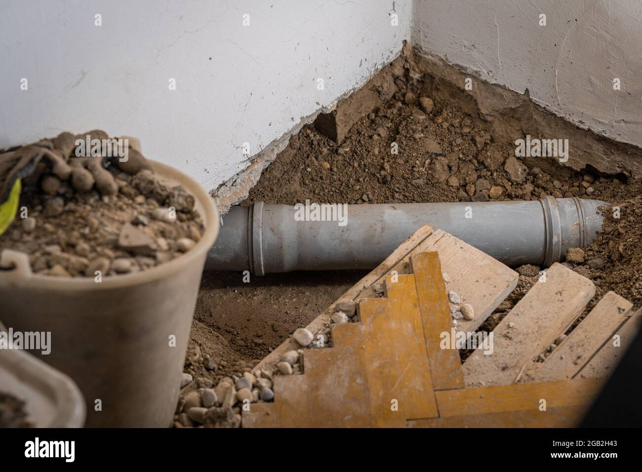 Fuite de tuyau d'égout en plastique dans un ancien appartement, trou ouvert  visible avec le parquet enlevé, le sable et les seaux autour, tuyau  d'évacuation exposé dans le sol Photo Stock -