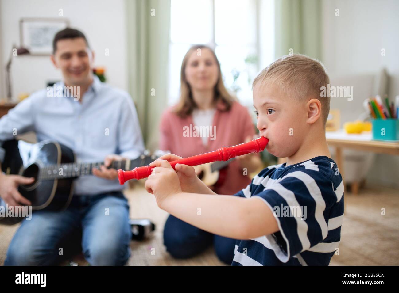 Gai Down syndrome garçon avec des parents jouant des instruments de musique, rire. Banque D'Images