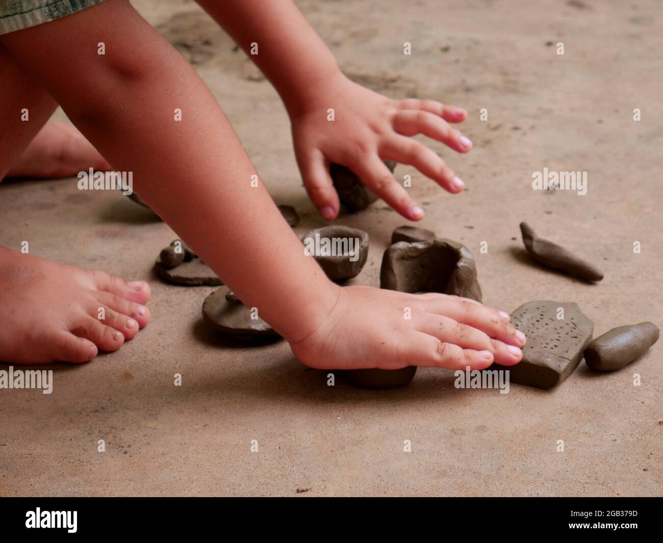 Les enfants qui font de la terre ont fait du jouet sur une surface en béton sans image du visage. Banque D'Images