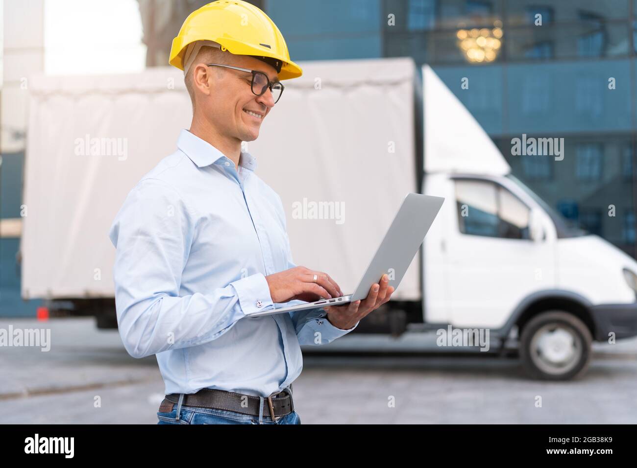 Entreprise. Ingénieur travailleur casque de protection utilisation des commandes de l'ordinateur portable Inspecteur du processus de travail Superviseur jaune casque à lunettes de sécurité Compagnie de transport de Banque D'Images