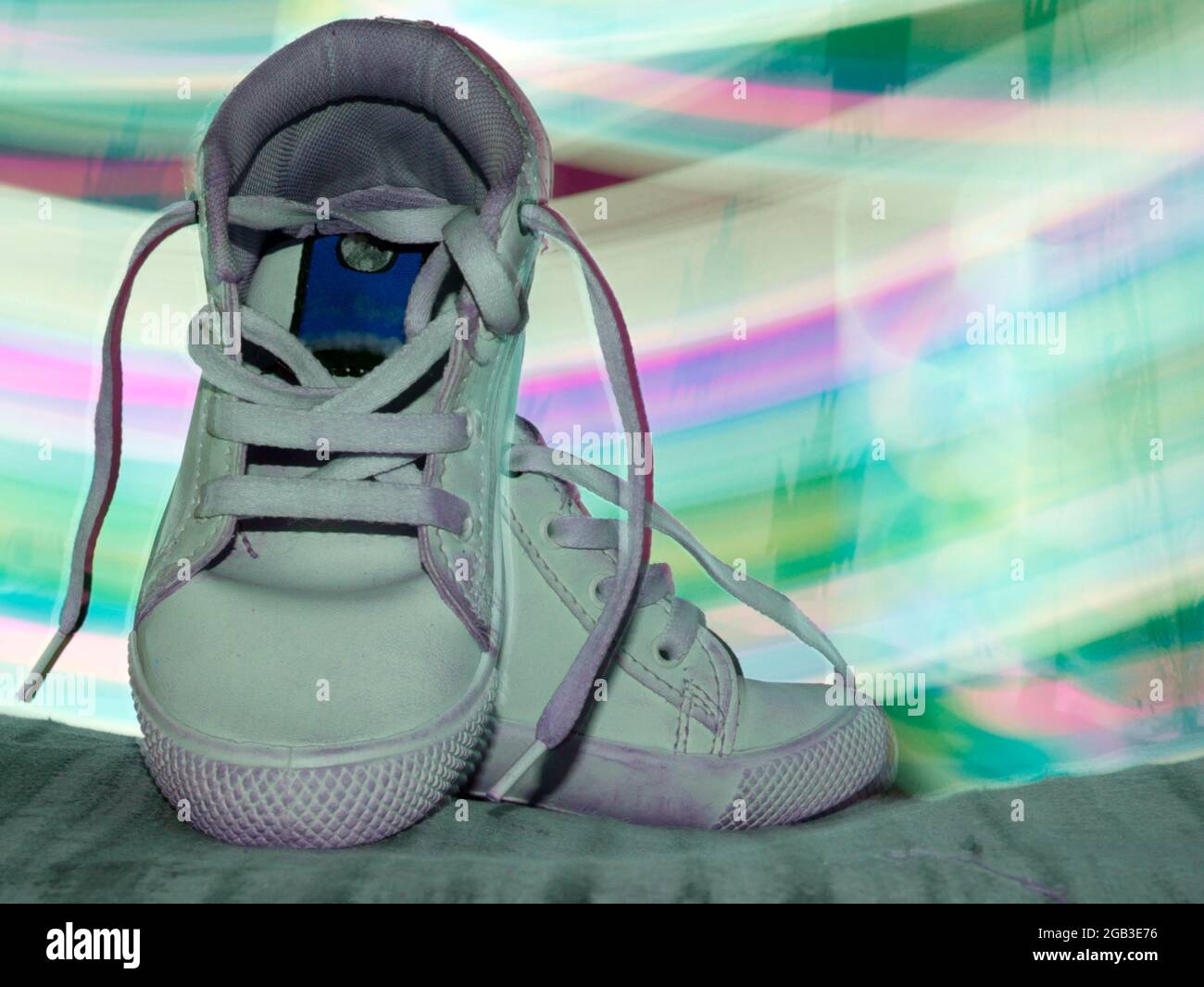 Chaussures de sport présentées avec un effet de lumière arc-en-ciel pour une image commerciale du produit. Banque D'Images