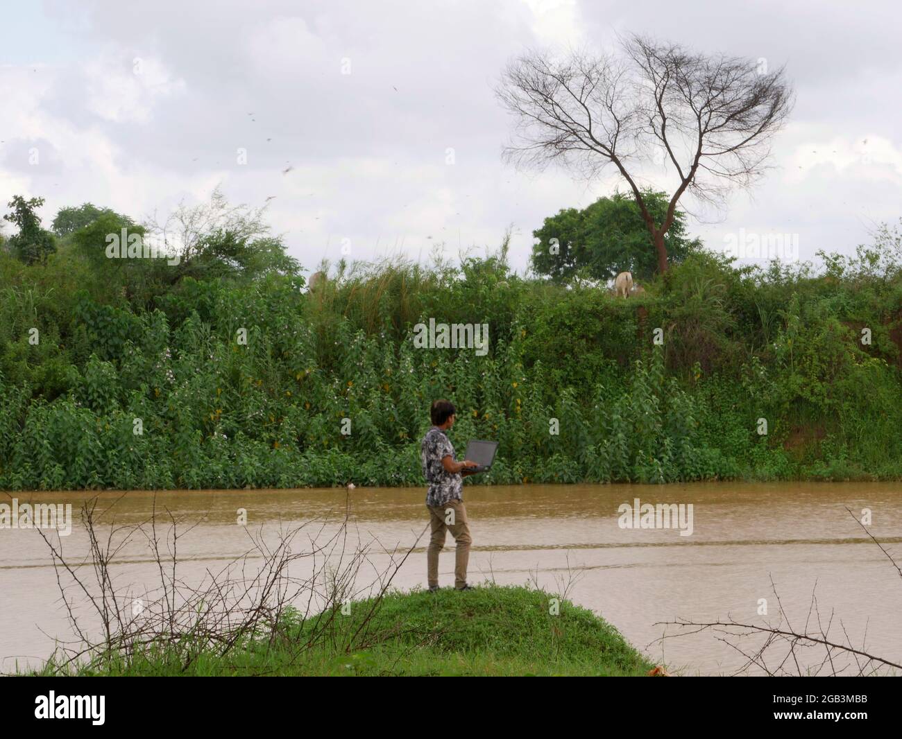 Homme asiatique tenant un ordinateur portable autour de la rive de la rivière vue incroyable sur le style de vie naturel. Banque D'Images