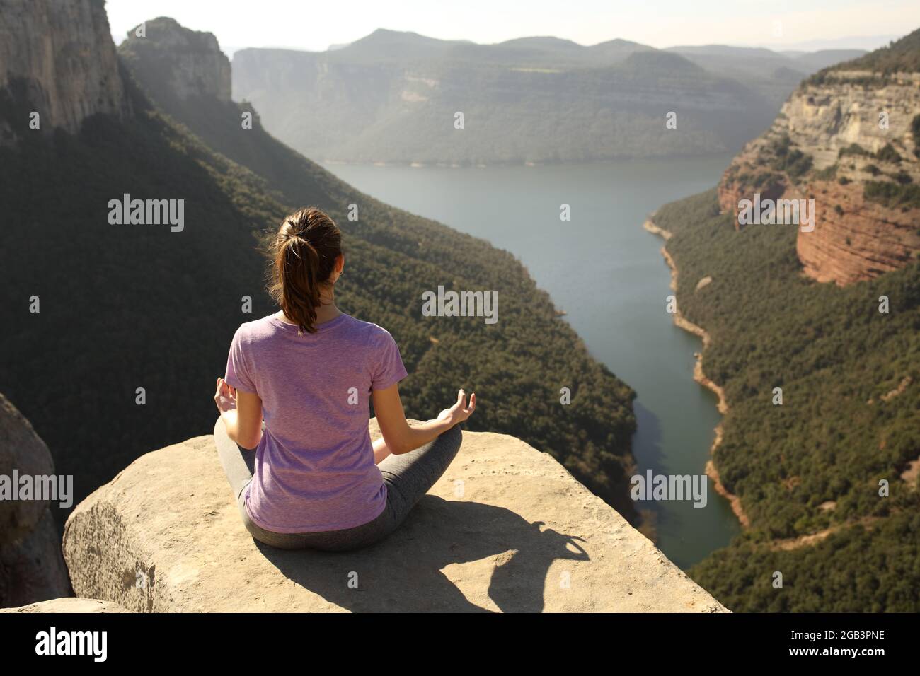 Vue arrière portrait du corps complet d'une femme faisant du yoga lotus poser sur le sommet d'une falaise Banque D'Images