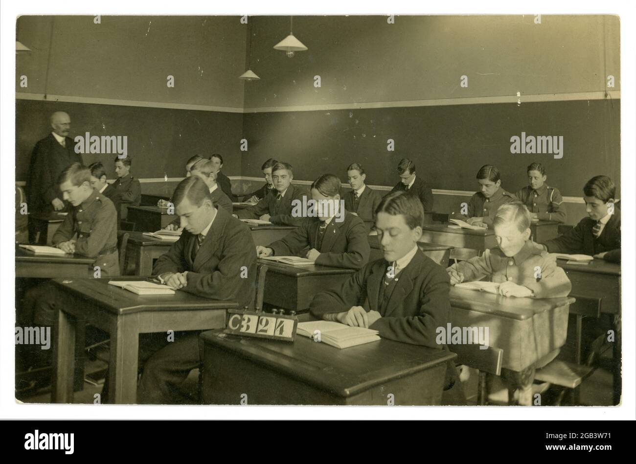 Carte postale originale du début des années 1900, datant de la première Guerre mondiale, de jeunes hommes assis à leur bureau dans une salle de classe, certains en uniforme, du studio de J&G Taylor, 631 Green Lanes, North London, Royaume-Uni vers 1914-1918 Banque D'Images
