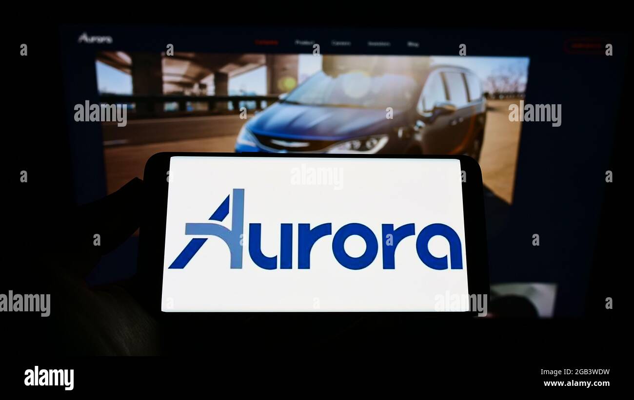 Personne tenant un téléphone mobile avec le logo de la compagnie de véhicules autopilotant Aurora innovation Inc. À l'écran devant la page Web. Mise au point sur l'affichage du téléphone. Banque D'Images