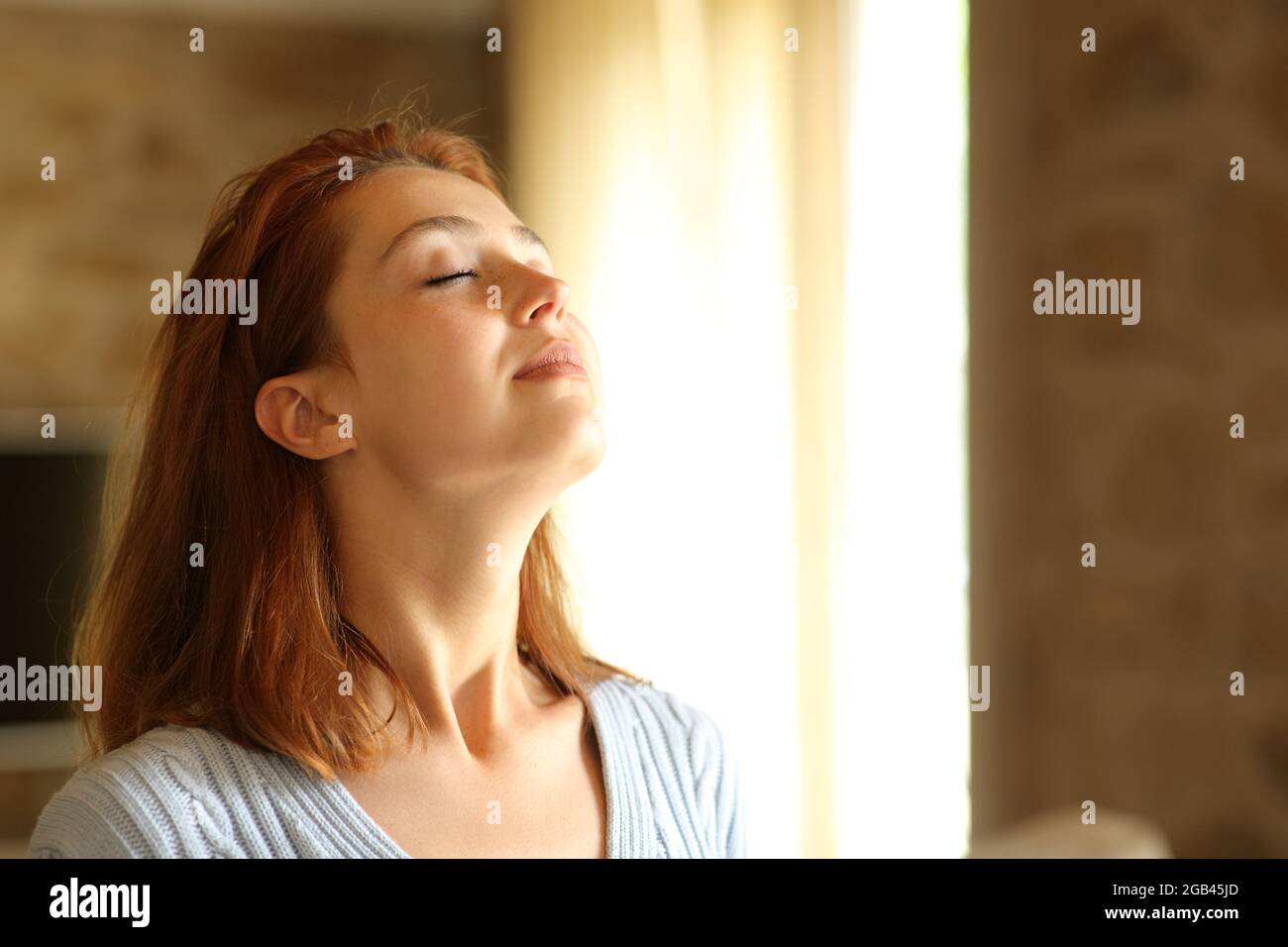 REDHEAD femme respirant de l'air frais dans le salon à la maison Banque D'Images