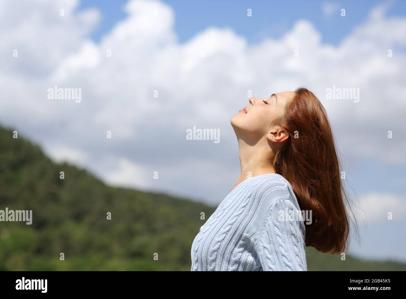 Profil d'une femme respirant de l'air frais dans la montagne avec un ciel nuageux Banque D'Images