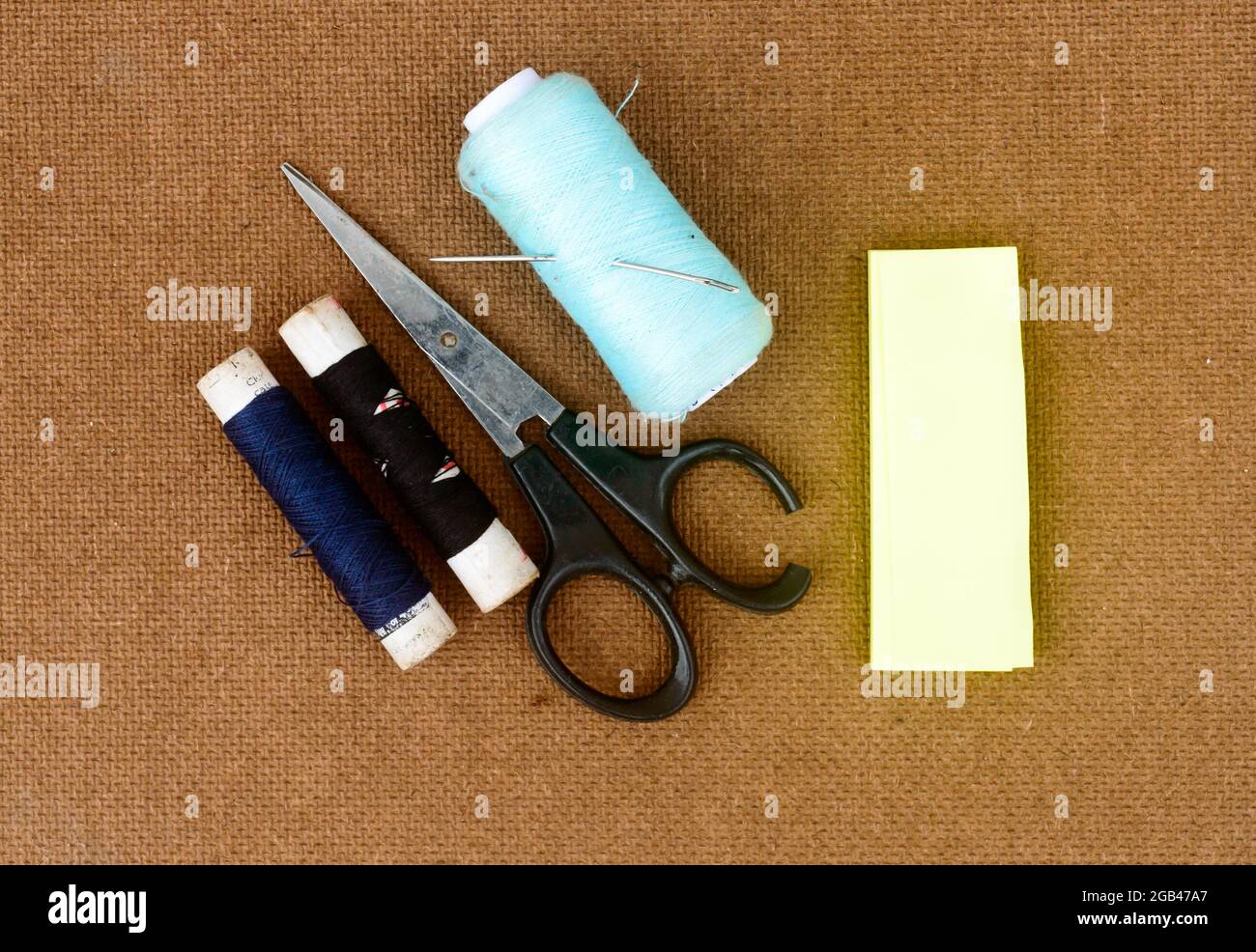 Ensemble d'outils et d'articles de couture pour le tricotage et le tissage placés sur un panneau de papier tissé de couleur brune. Bricolage Art et artisanat concept de fond. Banque D'Images