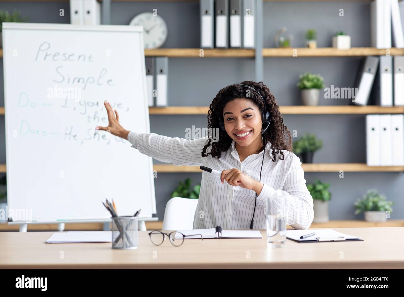 Femme afro-américaine dans le casque regardant la webcam, tirer pour blog en intérieur Banque D'Images