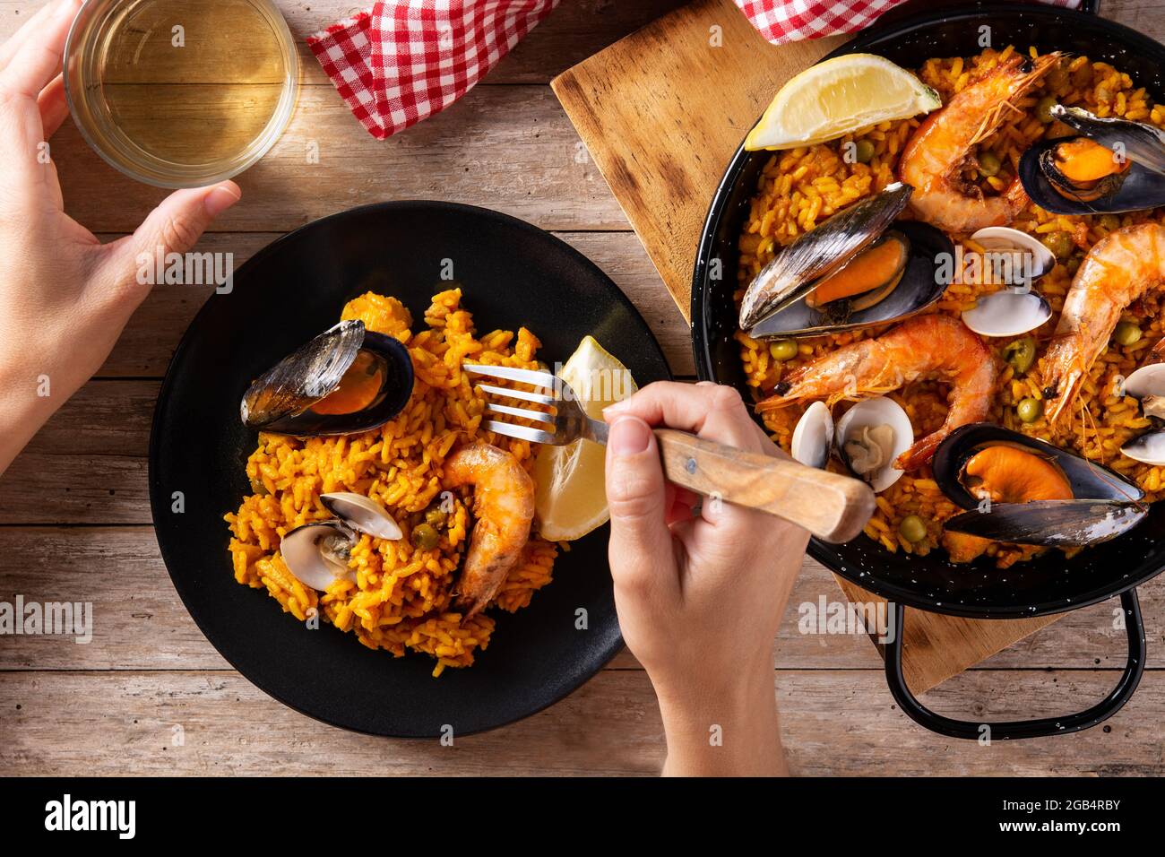 Femme mangeant de la paella espagnole de fruits de mer sur une table en bois Banque D'Images
