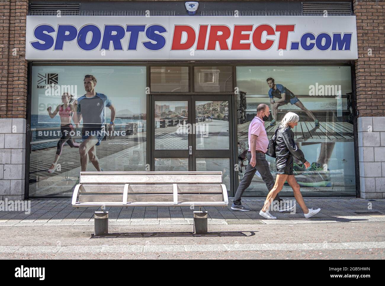 Les amateurs de shopping se prominent devant le magasin Sports Direct.com Sportswear sur Lombard Street à Belfast. Banque D'Images