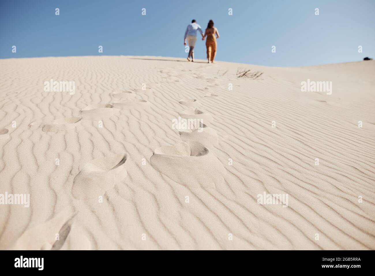 Jeune couple en train de marcher dans les dunes. Voyageur romantique marchant dans le désert du Sahara. Concept de mode de vie de voyage aventure. (séle Banque D'Images