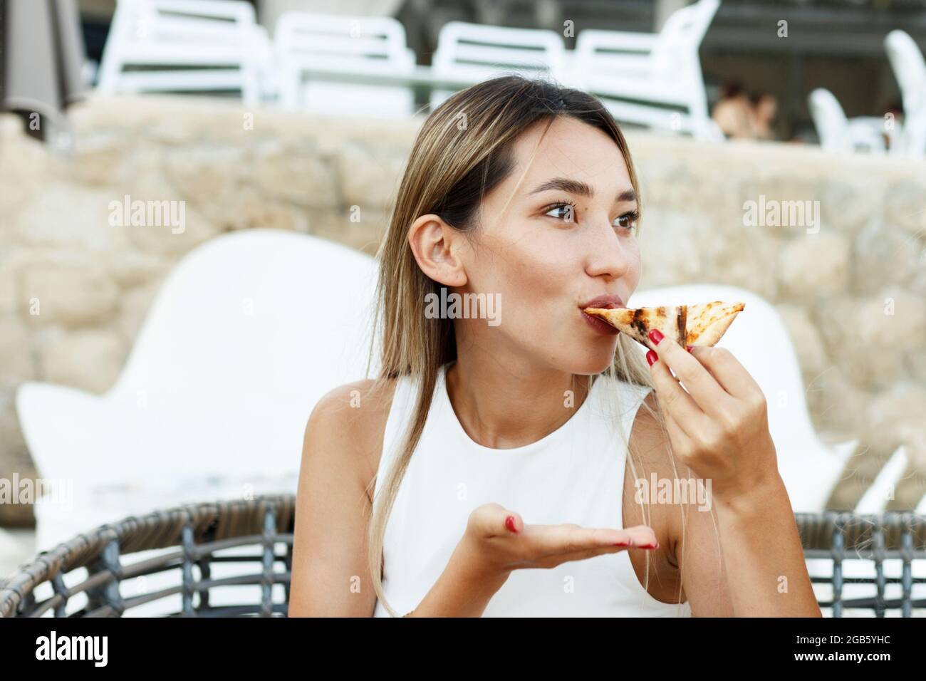 Portrait en gros plan d'une heureuse femme asiatique américaine qui mange de la pizza. Banque D'Images