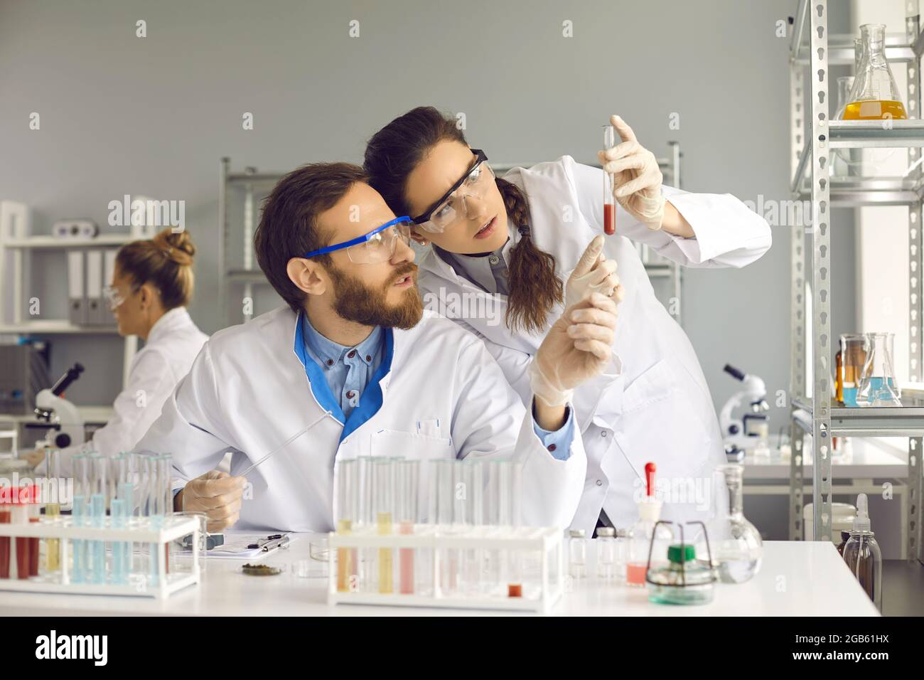 Équipe de scientifiques discutant de l'échantillon de sang dans un tube à essai en laboratoire Banque D'Images