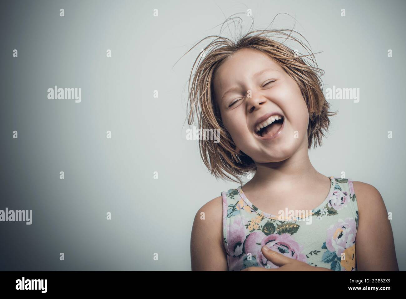 caucasien petite fille avec cheveux courts rire insouciant. studio portrait Banque D'Images