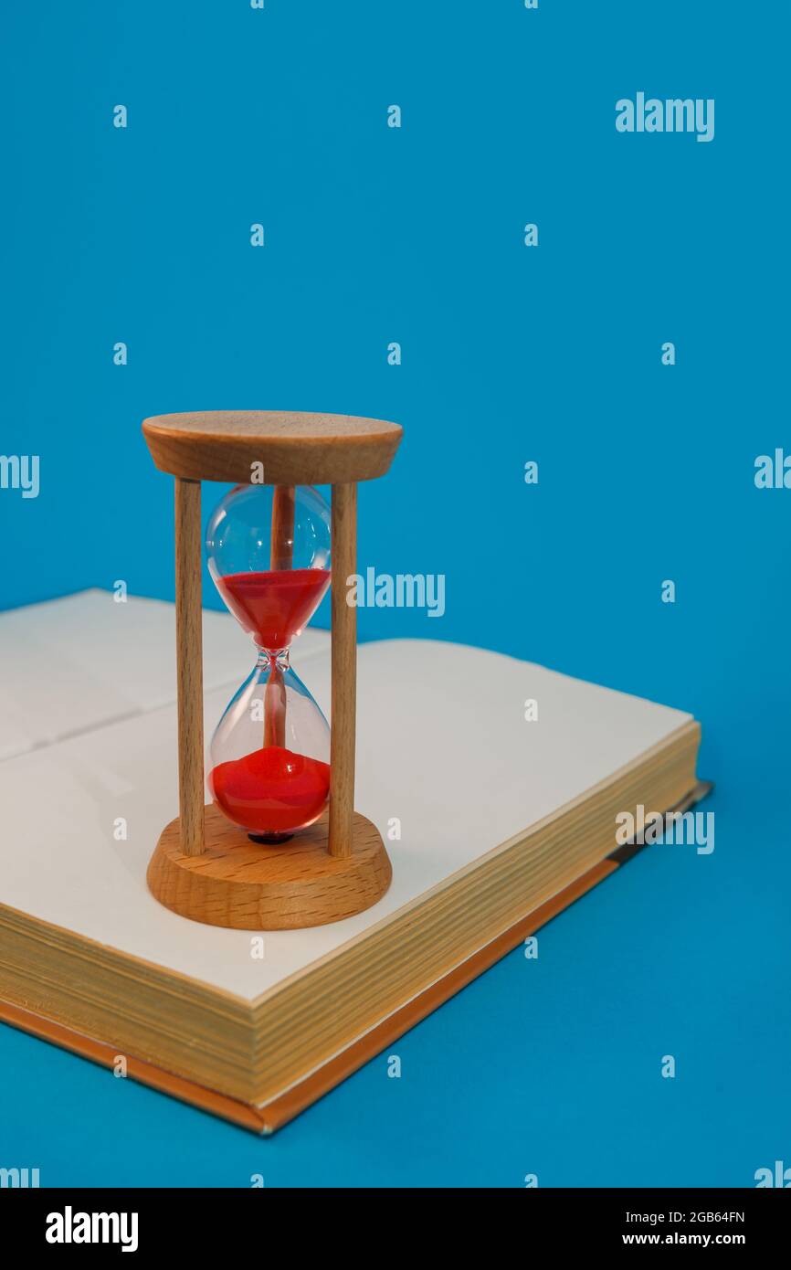 hourglass et livre sur fond bleu Banque D'Images