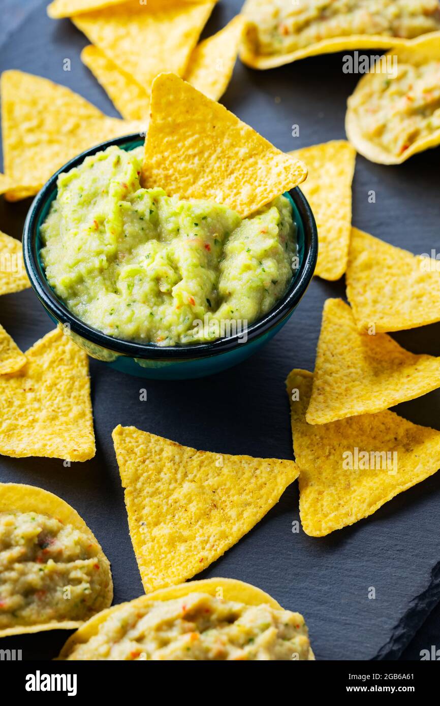 Puces de guacamole et de nachos sur fond sombre. Sauce guacamole avec
