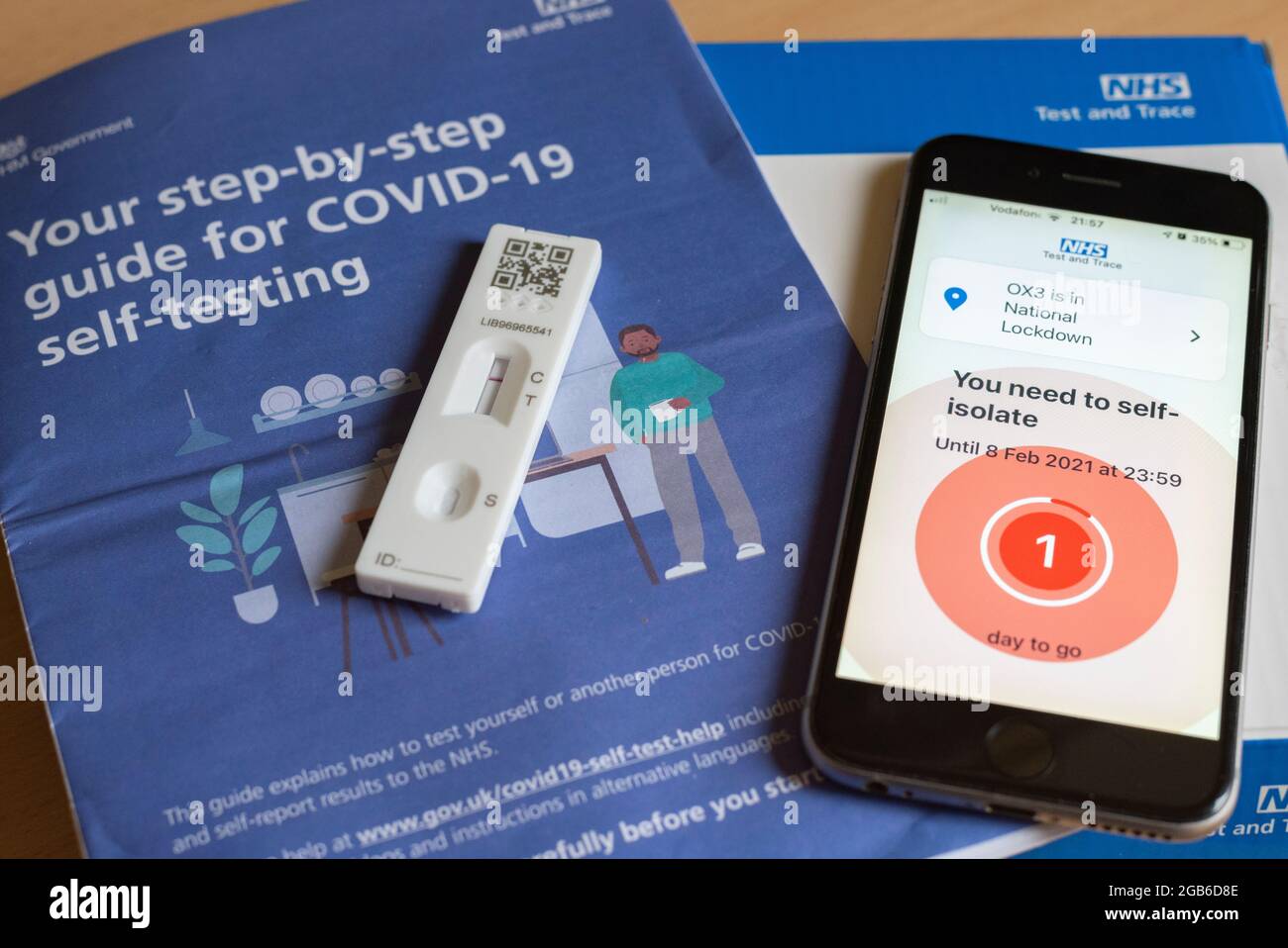 Un iPhone affichant un message d'auto-isolement pendant la pandémie Covid-19 en 2021, avec un test et un livret négatifs de Covid. Banque D'Images
