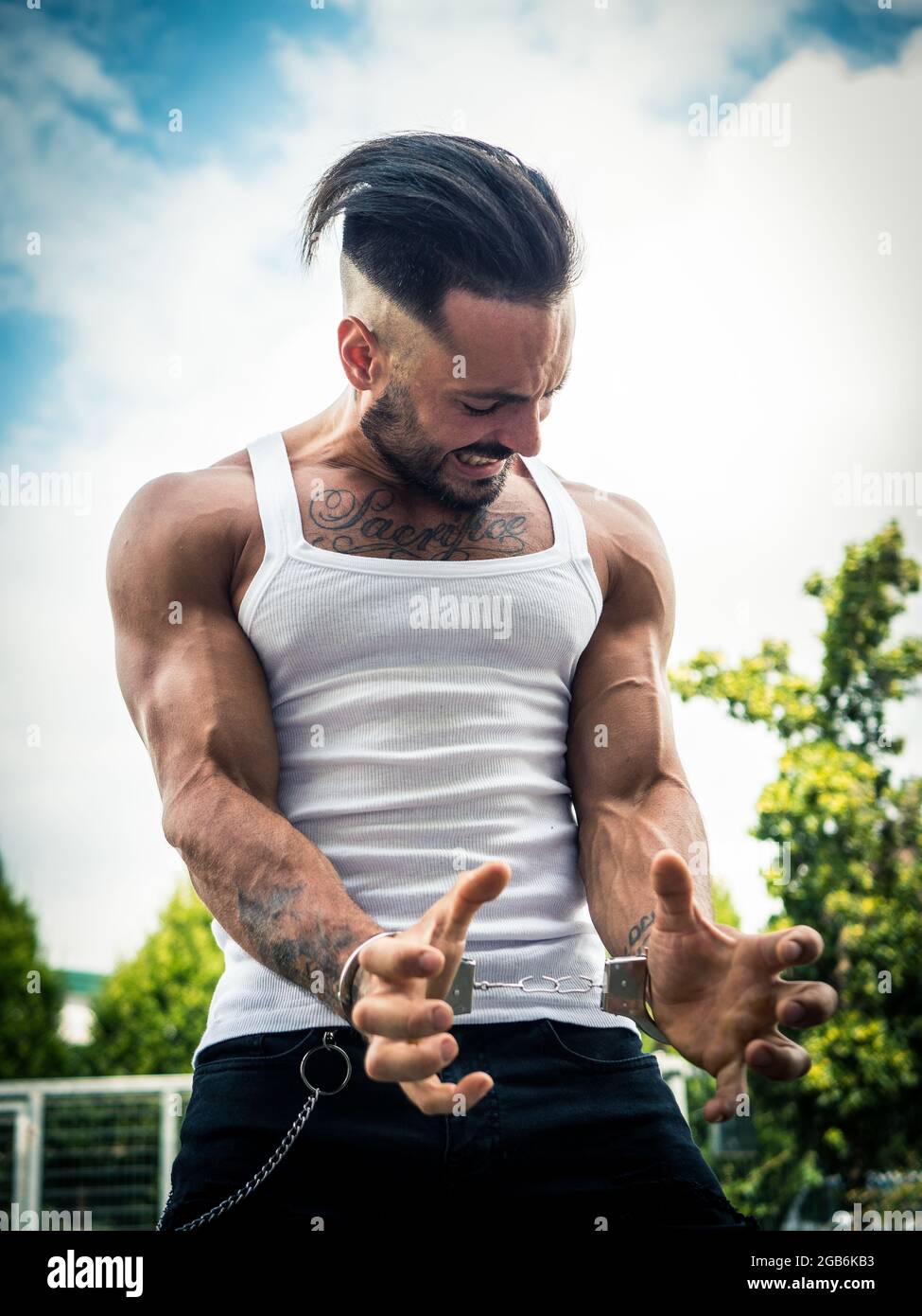 Un jeune homme fort déchirant les menottes dans le parc Banque D'Images