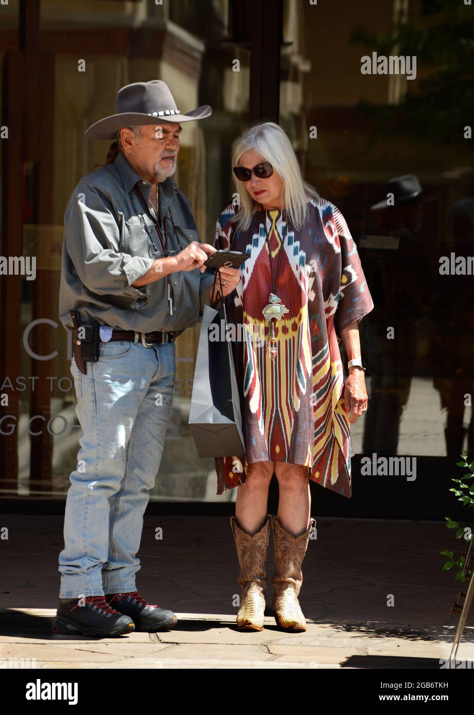 Un couple vêtu de vêtements occidentaux utilise son smartphone lorsqu'il visite Santa Fe, au Nouveau-Mexique. Banque D'Images