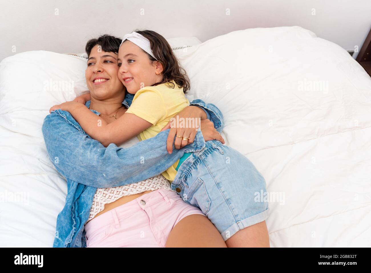 Mère latine et fille souriant dans le lit Banque D'Images