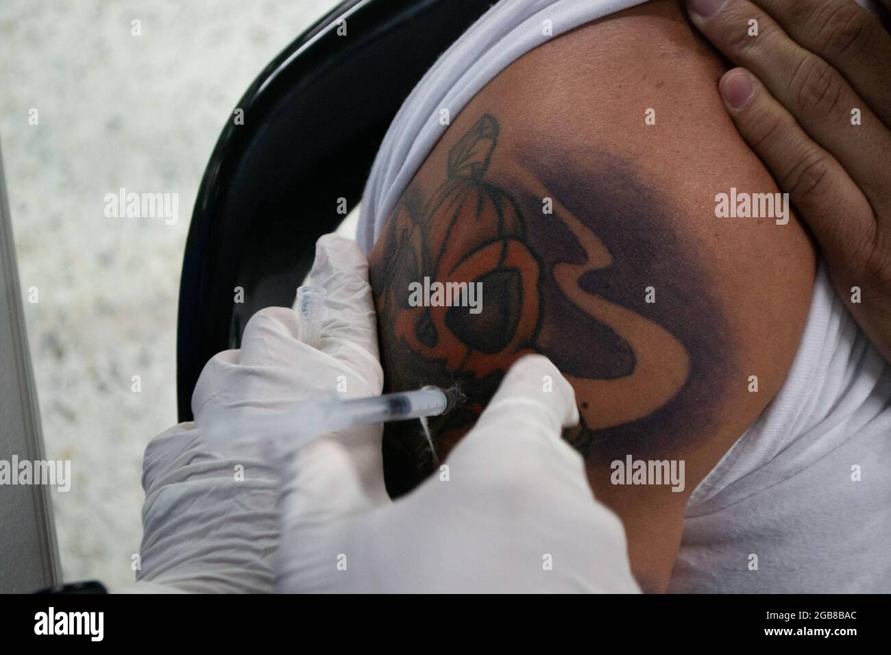 Bogota, Colombie. 2 août 2021. Un homme avec un tatouage de crâne de citrouille reçoit une dose du vaccin Moderna COVID-19 alors que les conducteurs de transport public et les personnes de 25 à 30 ans commencent leur phase de vaccination avec le nouveau vaccin Moderna COVID-19 contre la maladie du coronavirus à Bogota, Colombie, le 2 août 2021. Crédit : long Visual Press/Alamy Live News Banque D'Images