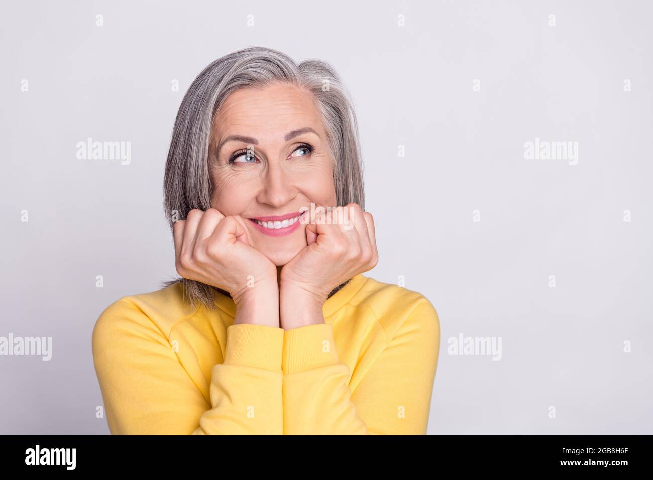 Photo de bonne humeur heureuse rêveuse charmante femme mature look copyspace adoring isolé sur fond gris couleur Banque D'Images