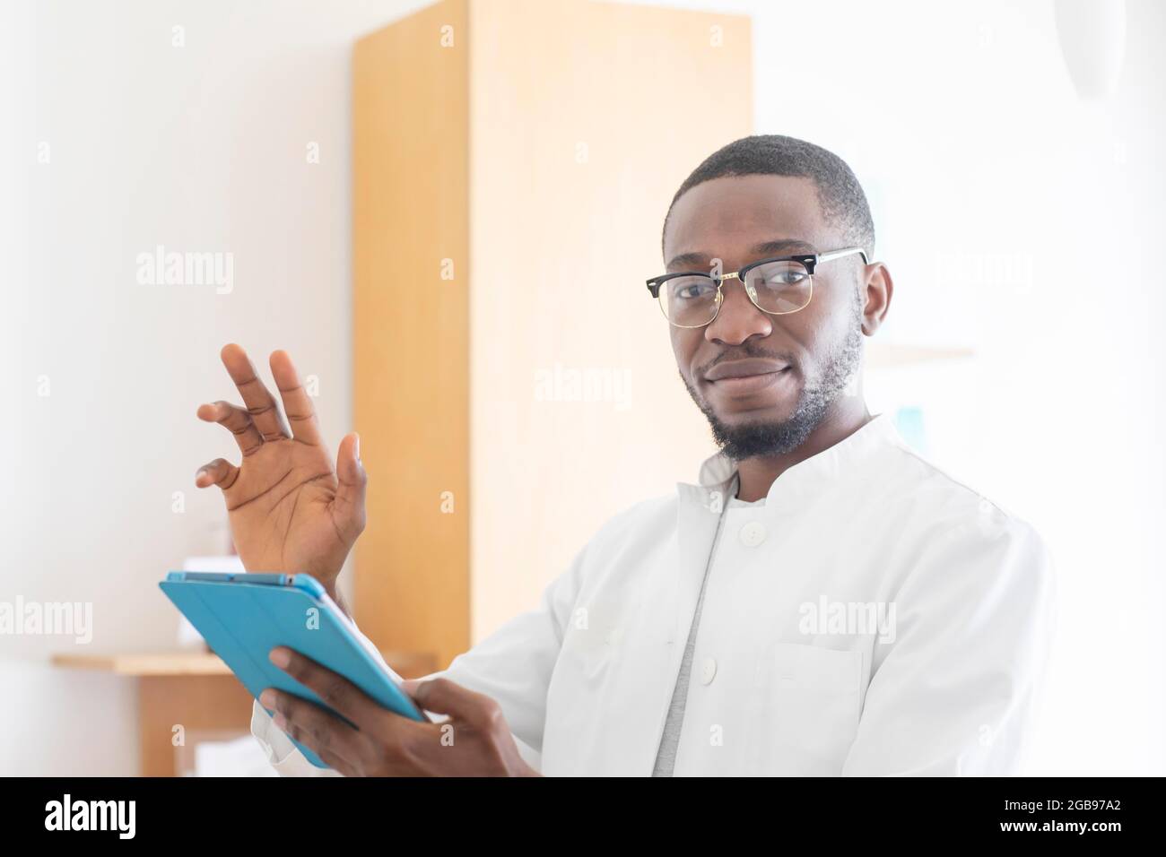 Jeune médecin noir avec une blouse et un comprimé expliquant dans la chirurgie, Freiburg, Bade-Wurtemberg, Allemagne Banque D'Images Jeune médecin noir avec une blouse et un comprimé expliquant dans la chirurgie, Freiburg, Bade-Wurtemberg, Allemagne Banque D'Images