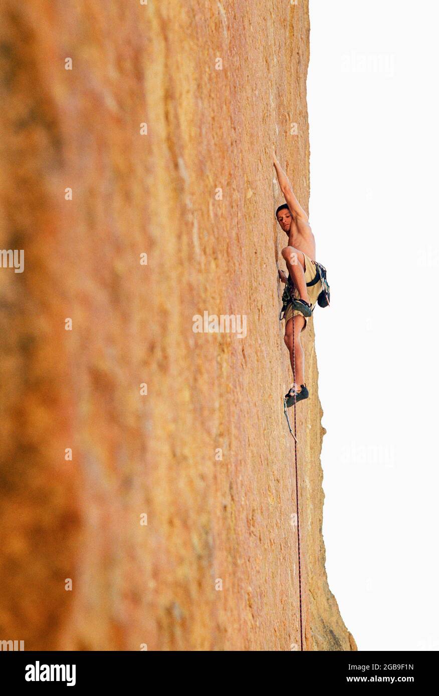Un jeune homme escalade sur une falaise verticale. Banque D'Images