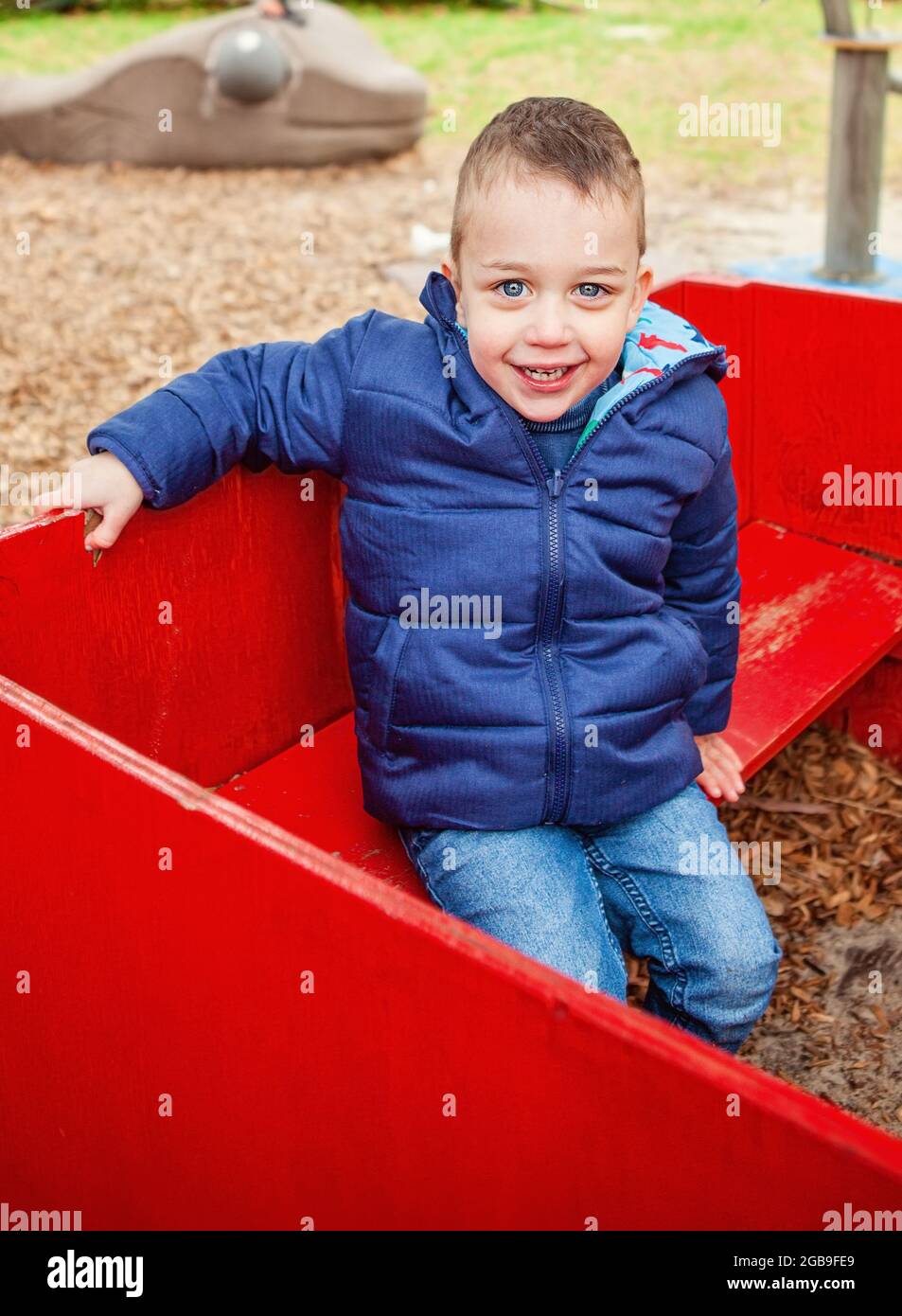 enfant assis à l'extérieur sur un équipement de jeu Banque D'Images