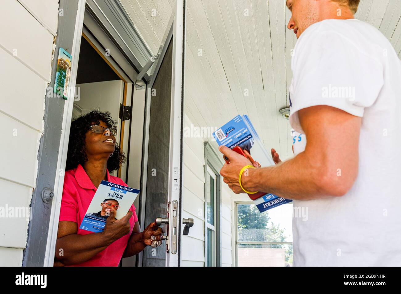 Aretha Wood, 59 ans, d'Akron, Ohio, parle avec le bénévole de Canvas, Eric Young, du vote pour Nina Turner sur son porche. Nina Turner est une candidate progressiste démocrate pour le 11e Congressional District de l'Ohio. Turner détourne contre un autre candidat démocrate, Shontel Brown, qui est un représentant d'un candidat démocrate plus traditionnel. Turner a été soutenu par Alexandria Ocasio-Cortez, Bernie Sanders, Cornel West et d'autres progressistes bien connus, parce que beaucoup pensent que Turner pourrait être un nouveau visage plus progressiste pour le Parti démocrate en Amérique. Banque D'Images