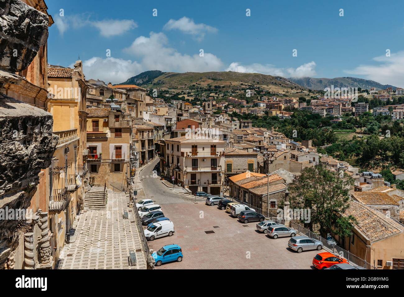 Caccamo, Sicile, Italie. Vue sur la ville médiévale populaire au sommet d'une colline et la Piazza Duomo avec des voitures.ville médiévale avec le célèbre impressionnant château normand. Banque D'Images