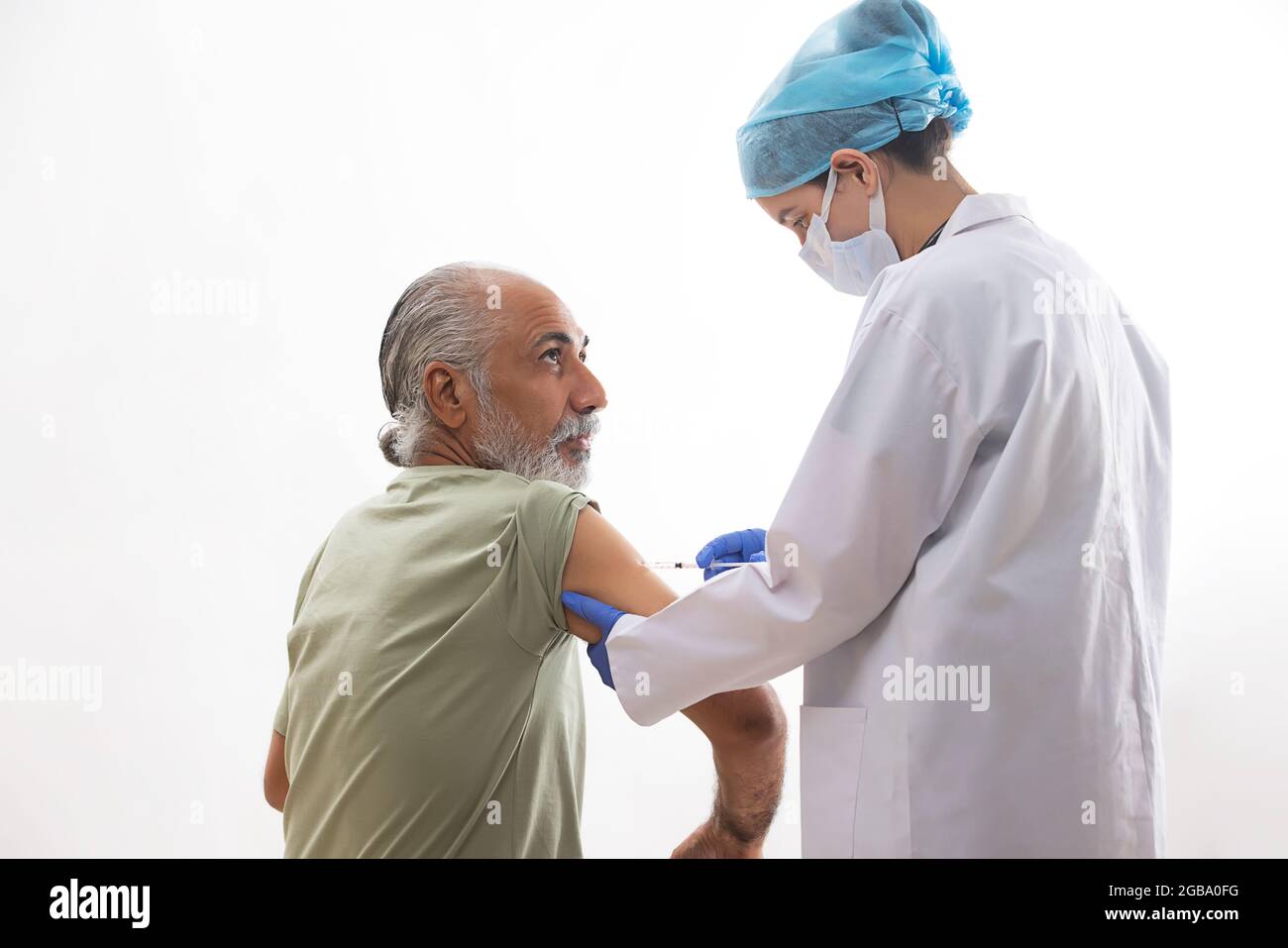 UN VIEIL HOMME VACCINÉ PAR UN PROFESSIONNEL DE LA SANTÉ Banque D'Images