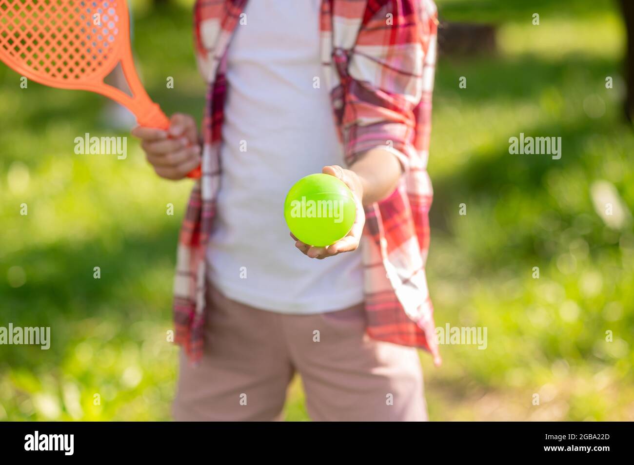 La main des enfants s'étire sur le ballon de tennis Banque D'Images