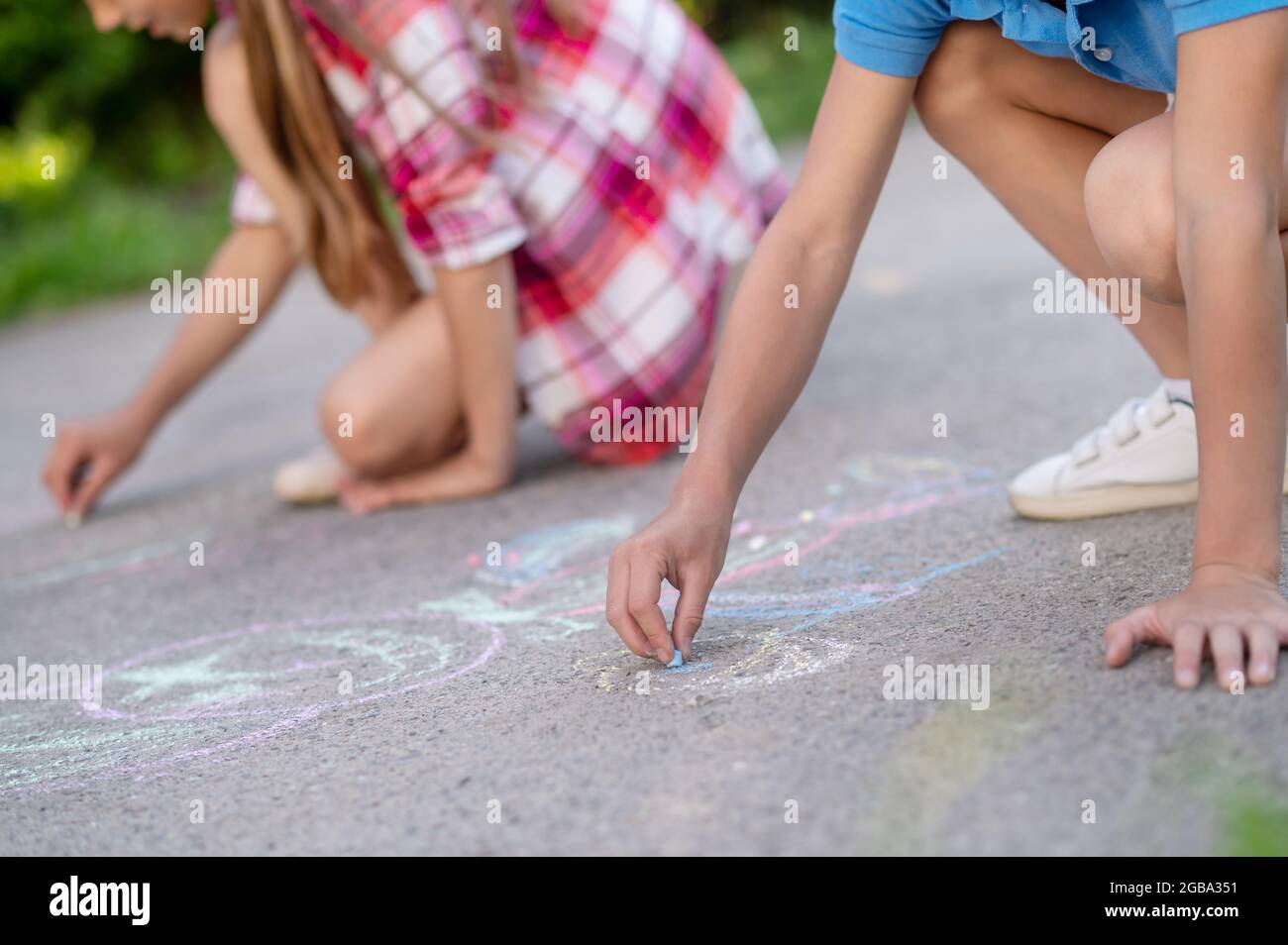 Les enfants dessinant avec des crayons sur l'asphalte Banque D'Images