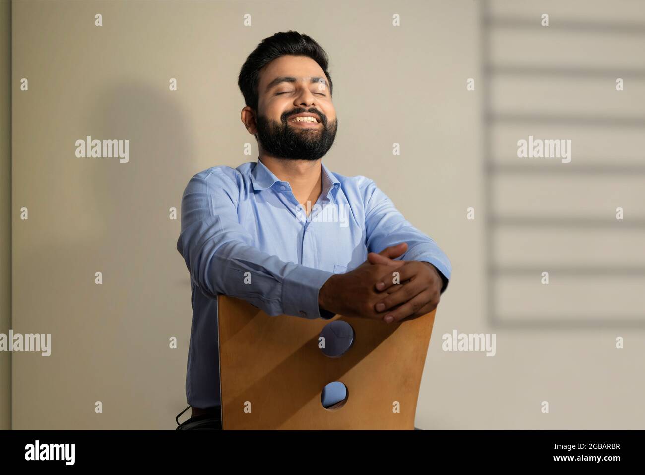 UN HOMME À BARBE HEUREUX ASSIS ET SE SENTANT HEUREUX Banque D'Images